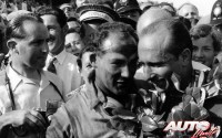 Hasta la llegada de los cascos integrales, los pilotos tenían que ponerle cara al polvo y a la suciedad que desprendían el resto de los coches a lo largo de la carrera, quedando marcado en su rostro no solo la dureza de la prueba, sino también las marcas de la batalla. Aquí podemos ver a Stirling Moss y a Juan Manuel Fangio celebrando su éxito, tras copar las dos primeras posiciones con sus Mercedes W196 en el GP de Gran Bretaña de 1955, disputado en el circuito de Aintree.